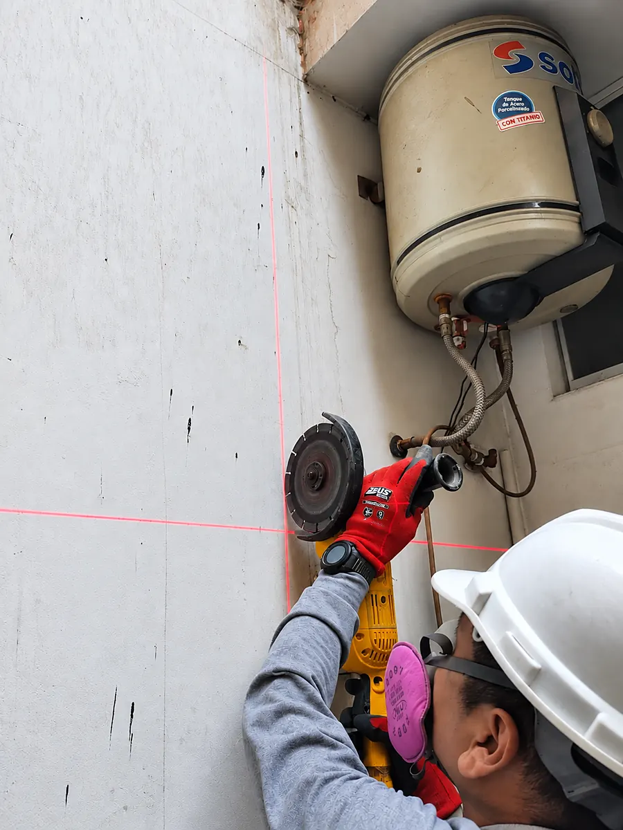 Técnico cortando el muro con amoladora siguiendo una línea láser