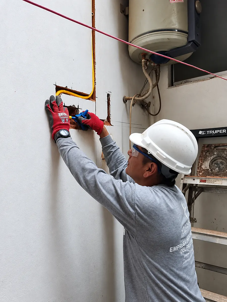 Técnico colocando la tubería y los accesorios dentro de la canaleta del muro