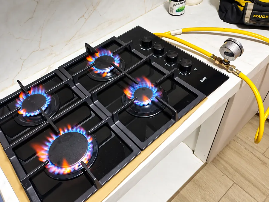 Cocina empotrada con cuatro quemadores encendidos con llama azul de gas natural